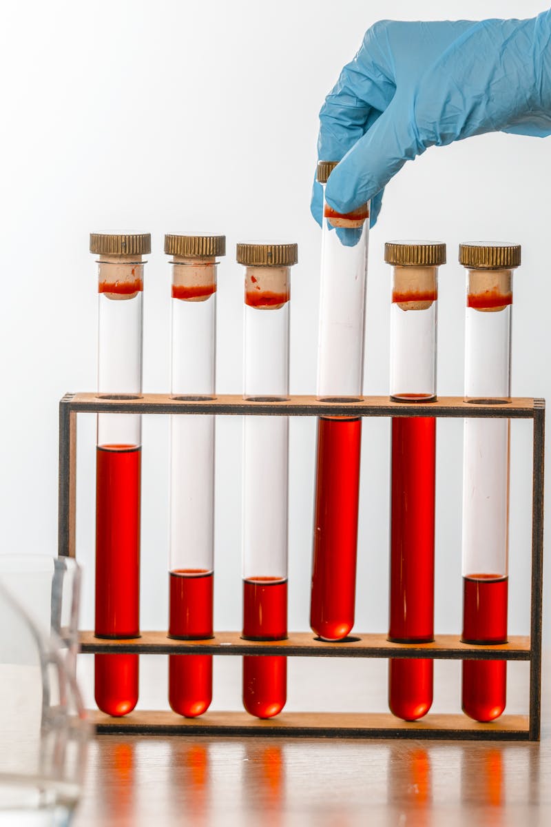 Close-up of gloved hand handling test tubes in a scientific laboratory setting.